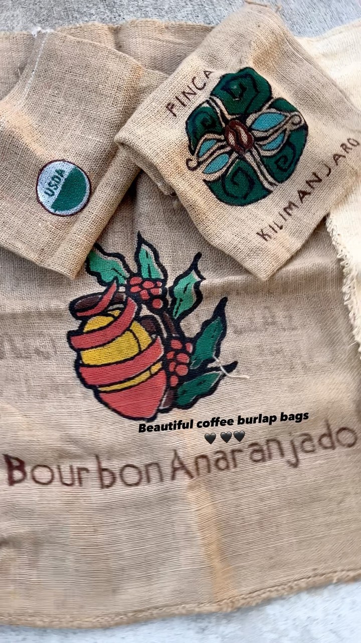 Stacked burlap sacks of coffee beans with roaster origin labels